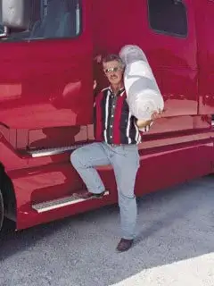 Truck driver entering red semi truck cab for truck mattress