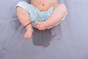 Baby sitting on clean mattress for mattress care guide