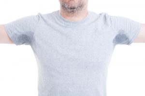 Person wearing gray t-shirt showing sweat stains for cleaning tips