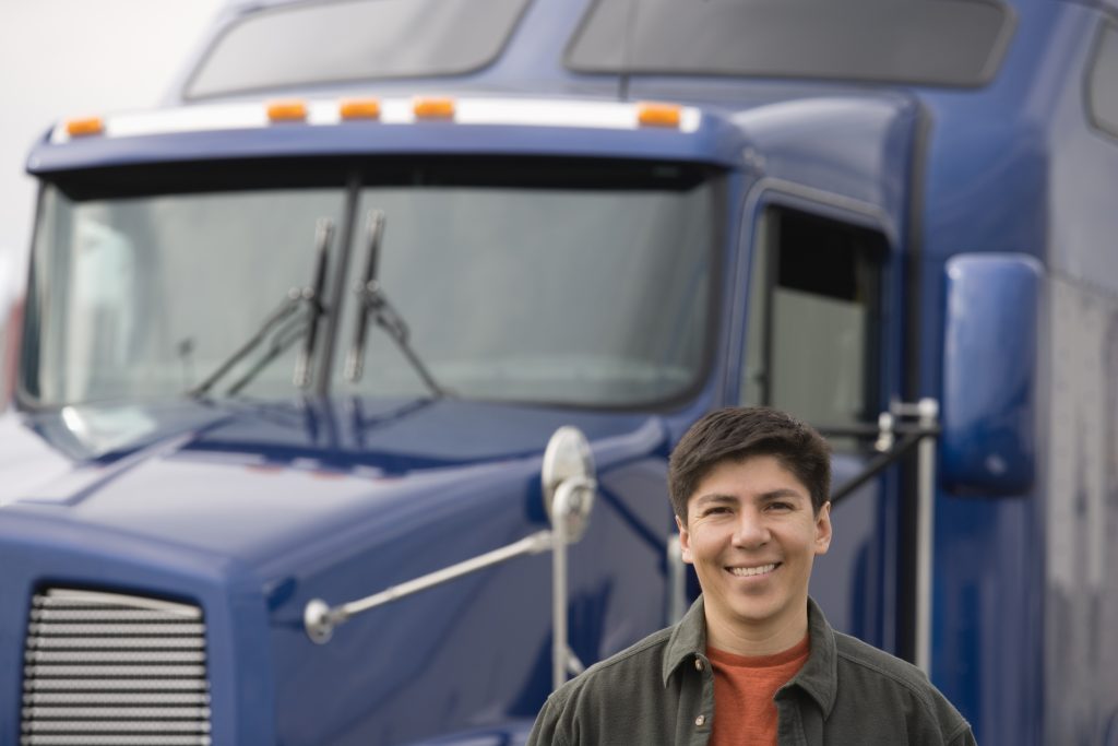 Smiling truck driver with blue semi