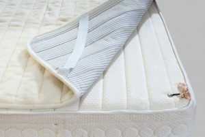 Mattress corner detail with striped pillow and white quilted cover
