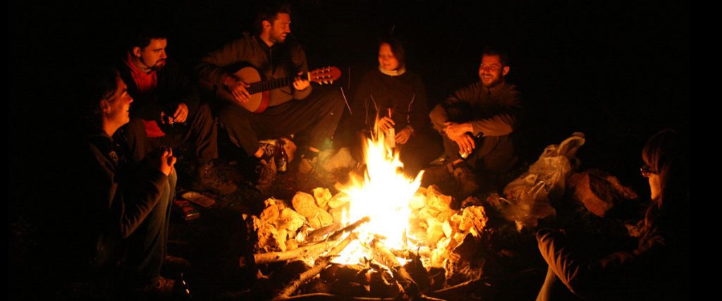 Friends around campfire at night camping