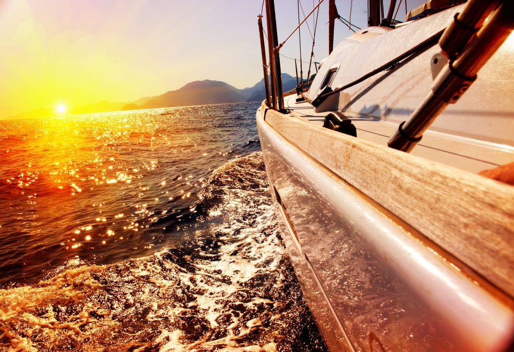 Yacht sailing into sunset on ocean for boat mattress lifestyle
