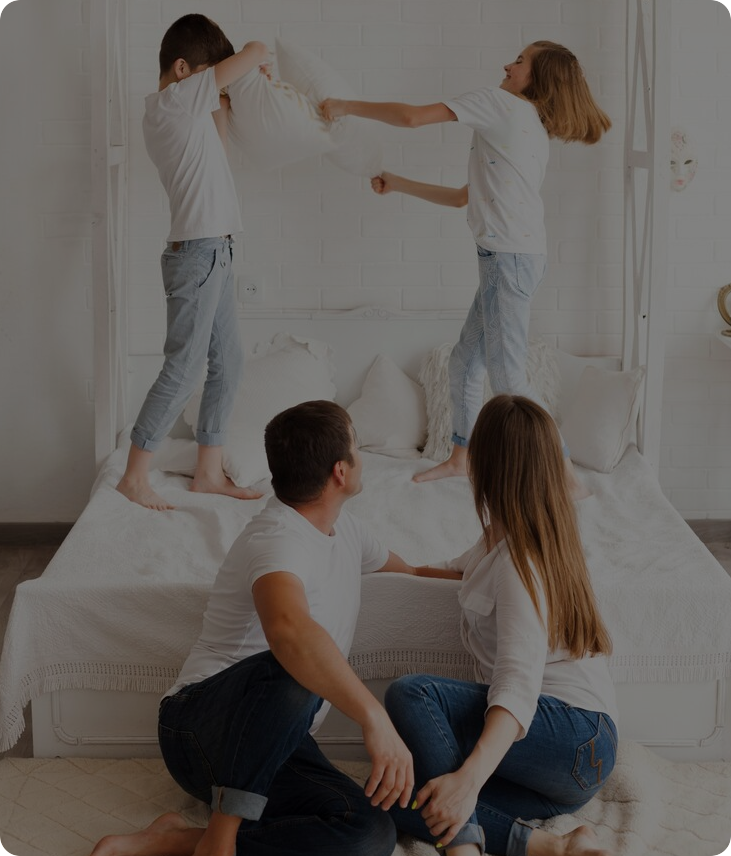 Happy family having pillow fight on mattress in bedroom